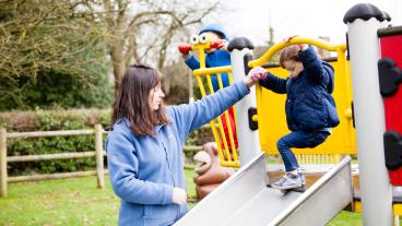 Kvinna leker med barn i lekpark